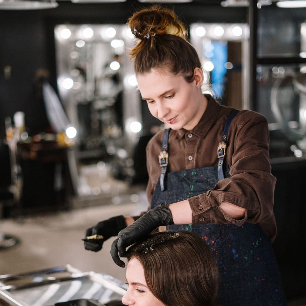 Colorist applying hair color in a salon