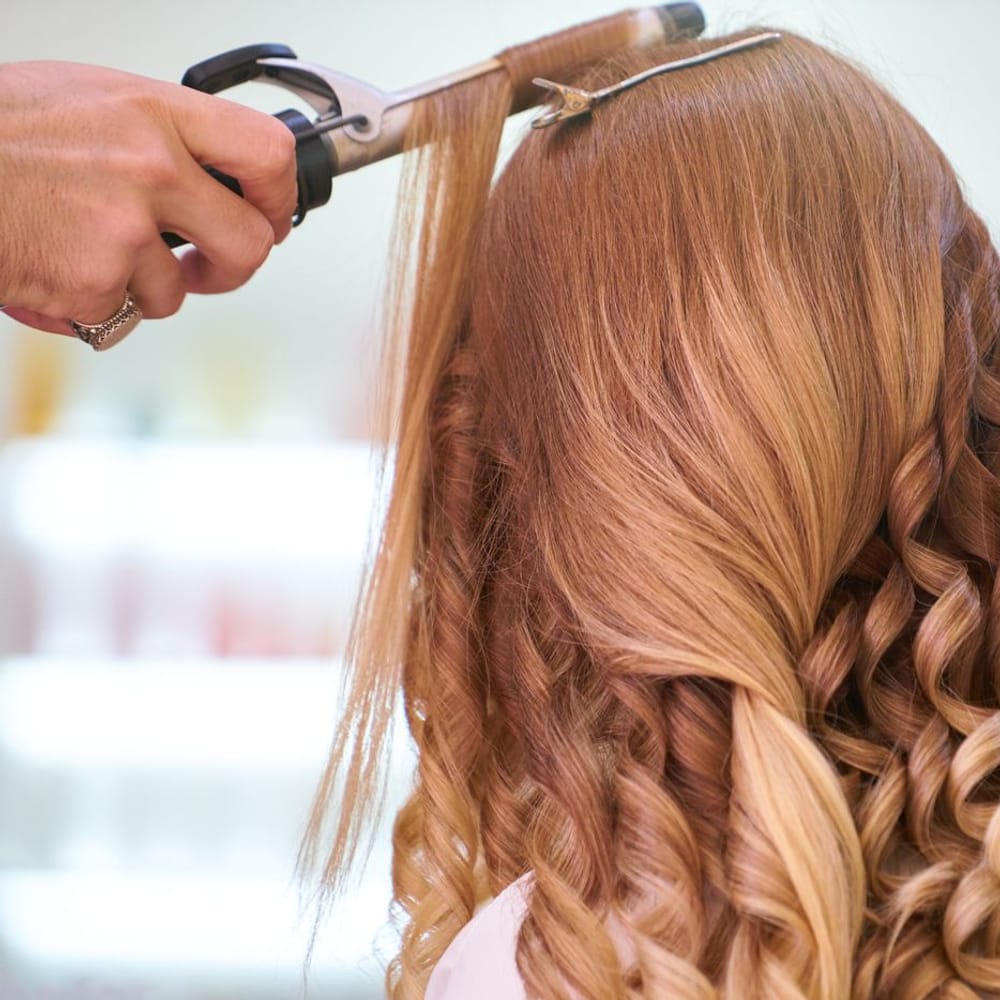 Stylist curling long blonde hair into defined ringlets