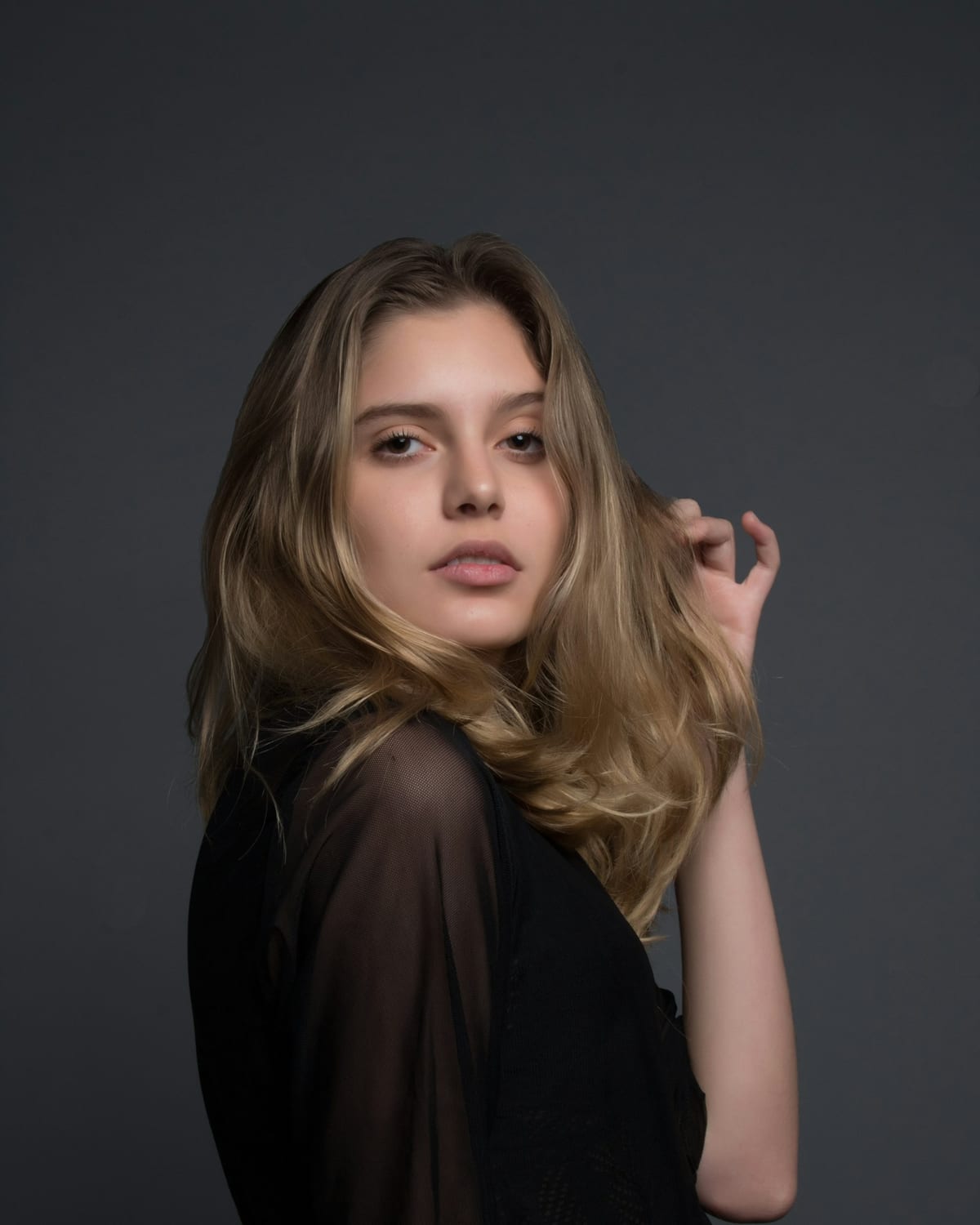 Woman with highlighted wavy hair, hand in her hair